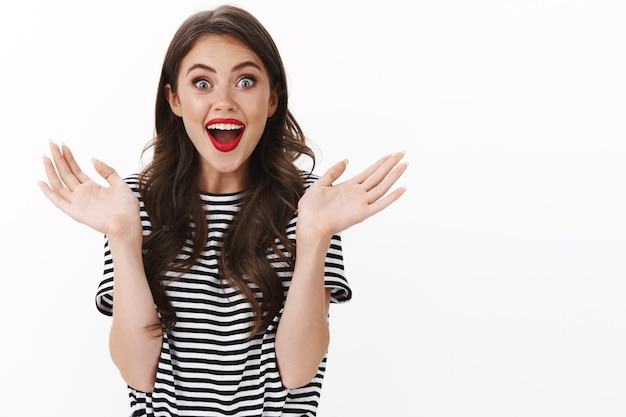 Photo gratuite une femme séduisante, joyeuse, amusée et amusée serrant les mains, amusée, regardant une merveilleuse pièce de théâtre, la bouche ouverte fascinée et prise en embuscade, voir une performance à couper le souffle, des applaudissements heureux