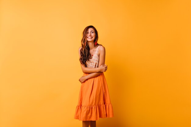 Femme sensuelle de bonne humeur posant dans des vêtements d'été. Fille aux cheveux longs avec joli sourire s'amuser en studio.