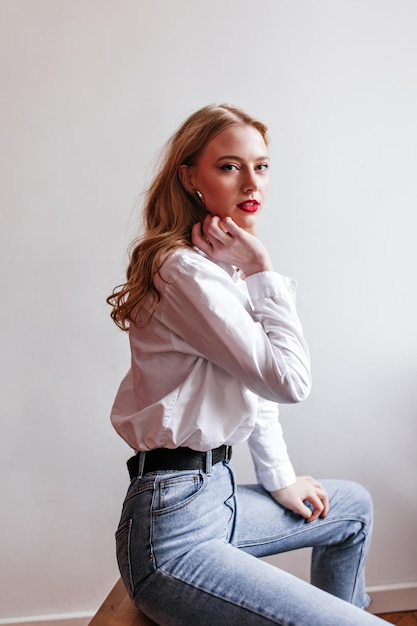 Femme sensuelle en jeans regardant la caméra Prise de vue en studio d'une magnifique fille blonde en chemise blanche