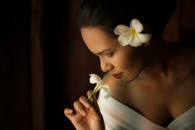 Femme sentant une fleur blanche à proximité