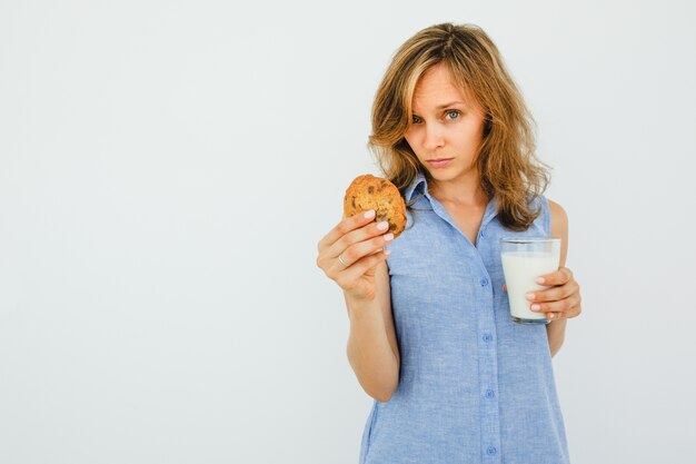 Femme sérieuse avec du verre de lait proposant un biscuit