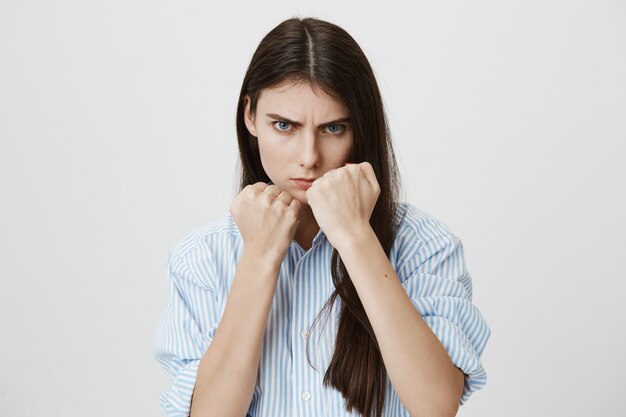 Femme sérieuse lever les mains en pose de boxeur, combat