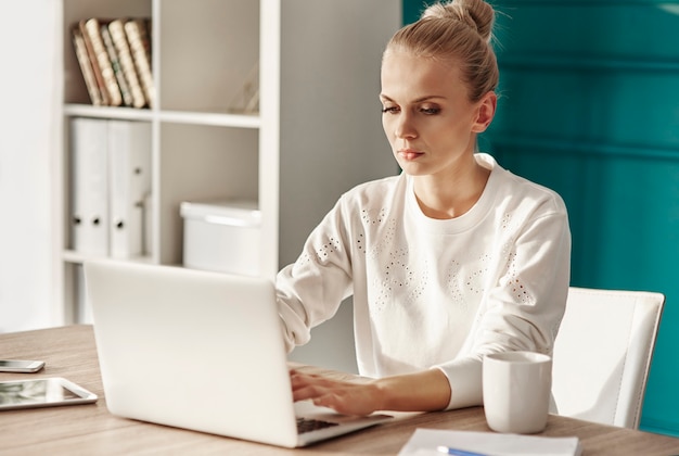 Femme sérieuse avec ordinateur portable travaillant au bureau à domicile