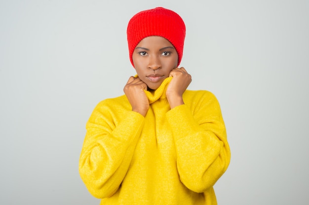 Femme sérieuse portant un pull jaune vif et un chapeau rouge