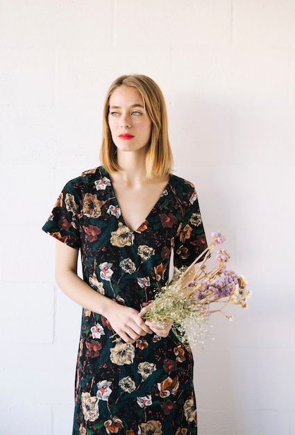 Femme sérieuse sensuelle avec bouquet de plantes sèches