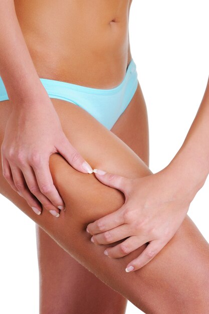 La femme serre la peau des mains sur la hanche pour vérifier la cellulite. Partie du corps féminin. Vue de côté.