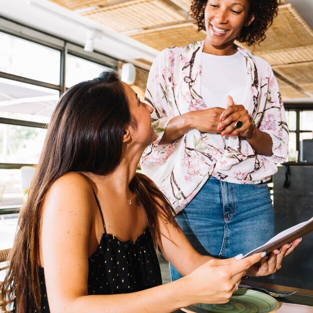 Femme serveur prenant les commandes d&#39;une jeune cliente au restaurant