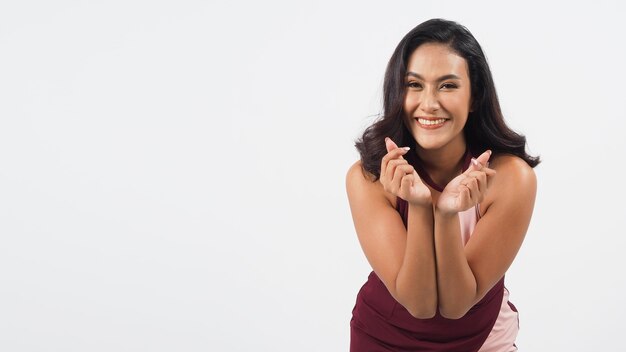 Femme sexy asiatique faisant un signe de main de mini coeur ou un coeur de doigt isolé sur fond blanc. elle a la peau bronzée, montre le concept d'amour.