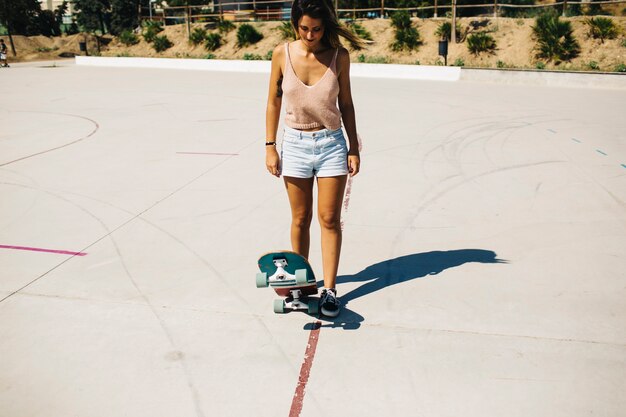 Femme avec skateboard regardant vers le bas