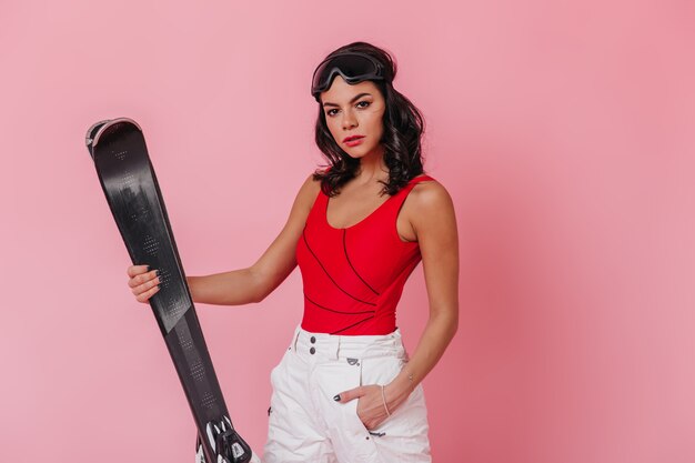 Femme avec des skis debout avec la main dans la poche