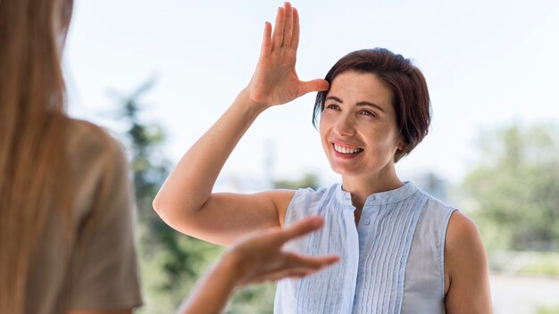 Femme Smiley conversant à travers la langue des signes à l'extérieur