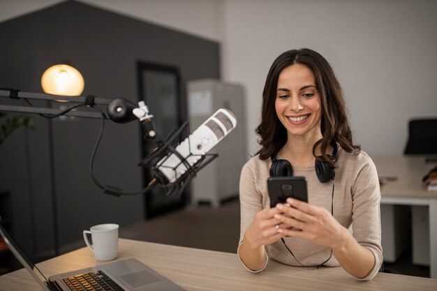 Femme Smiley faisant un podcast à la radio avec un microphone et un smartphone