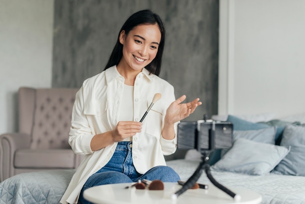 Femme Smiley faisant un vlog sur le maquillage à l'intérieur