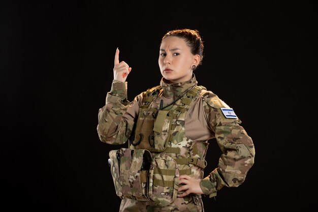 Femme soldat en camouflage sur le mur noir