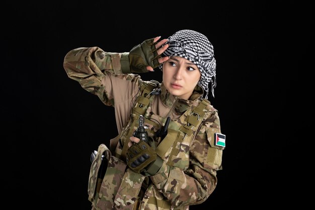 Femme soldat effrayée en uniforme militaire avec mur noir grenade