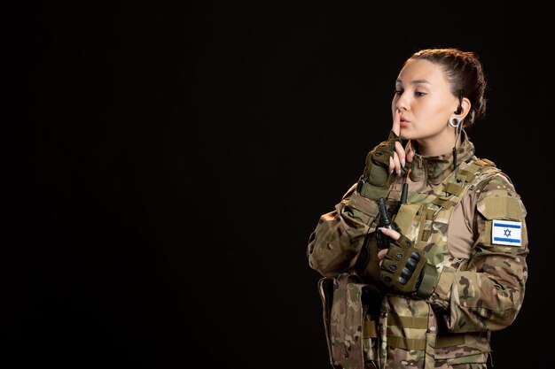 Femme soldat en tenue de camouflage avec grenade sur le mur noir