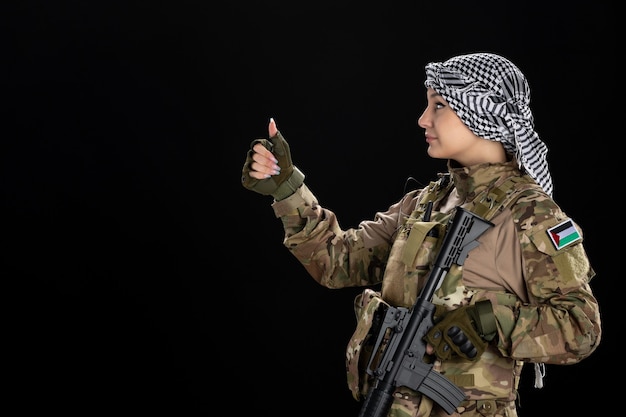 Femme soldat en uniforme militaire avec fusil sur le mur noir