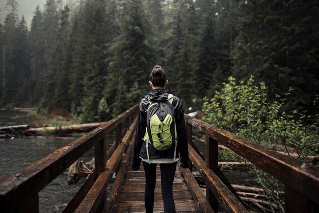 Femme avec son sac à dos, debout sur le pont en bois