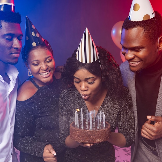 Femme soufflant des bougies sur son gâteau joyeux anniversaire