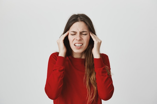 Femme souffrant de migraine, frotter les tempes et grimacer les yeux fermés, ressentir des maux de tête