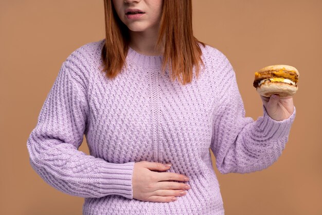 Femme souffrant de troubles de l'alimentation essayant de manger un hamburger