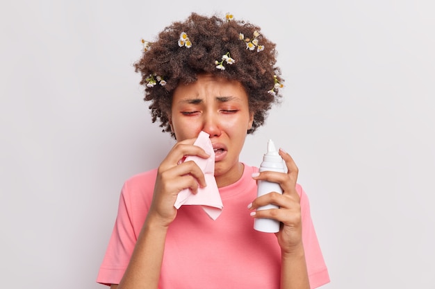 Une femme souffre d'allergies saisonnières se mouche dans une serviette utilise un aérosol a des problèmes de santé les yeux rouges réagit à l'allergène isolé sur blanc