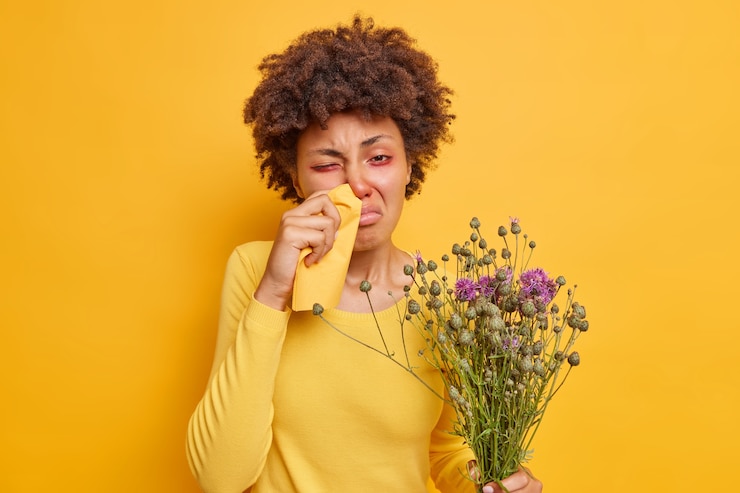 Photo gratuit une femme souffre de rhinite allergique se frotte le nez avec une serviette tient un bouquet de fleurs sauvages se sent mal pose sur un jaune vif