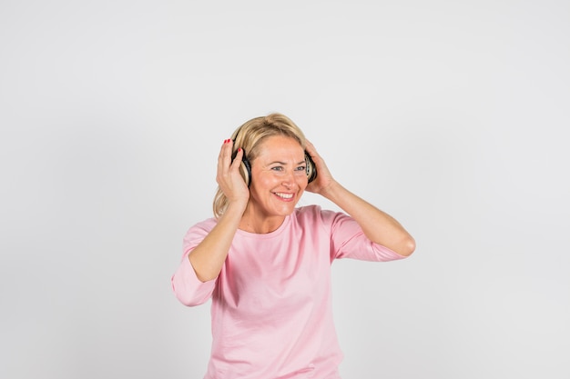 Femme souriante âgée en chemisier rose avec un casque