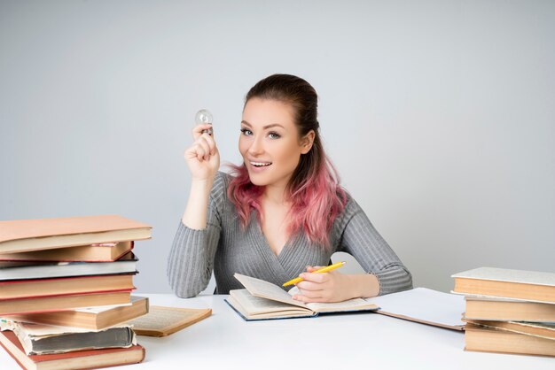 Femme souriante avec une ampoule et un crayon jaune dans les mains