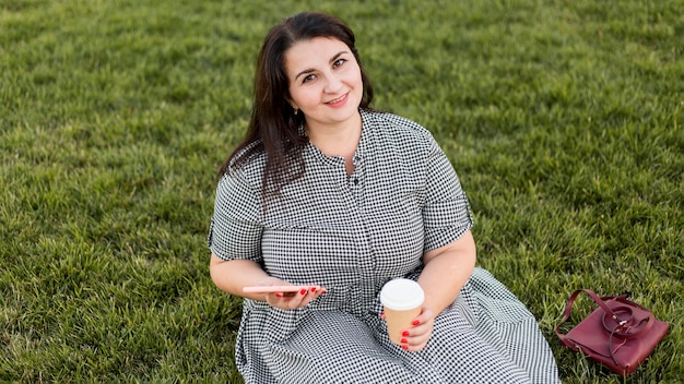 Photo gratuite femme souriante à angle élevé assis sur l'herbe