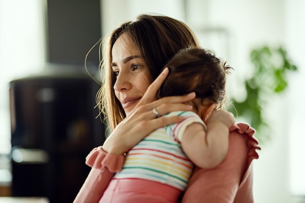 Femme souriante appréciant la maternité et tenant sa petite fille à la maison