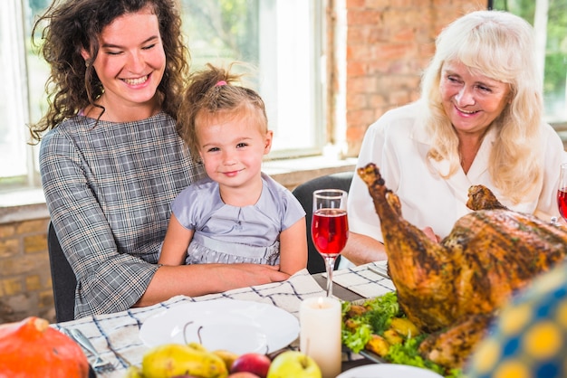 Femme souriante assise avec un enfant à la table près d&#39;une vieille dame