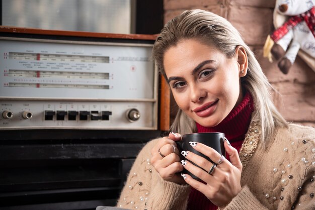 Une femme souriante assise et tenant une tasse de café