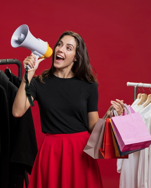 Femme souriante au shopping en criant avec un mégaphone