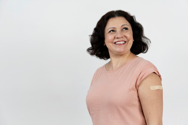 Femme souriante avec un bandage sur le bras après le vaccin