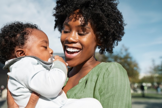 Femme souriante et bébé mignon à l'extérieur