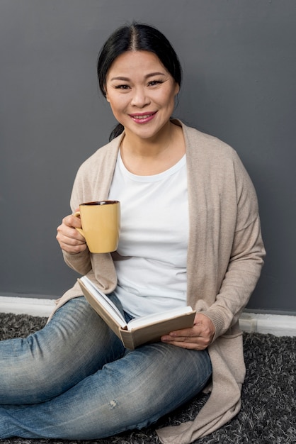 Femme souriante, boire du café et lire