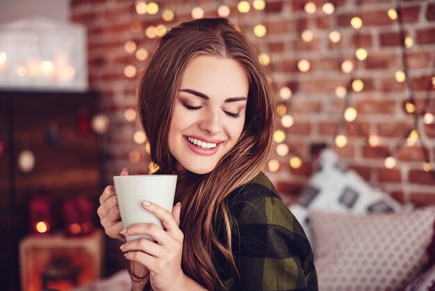Femme souriante, boire du café à la maison