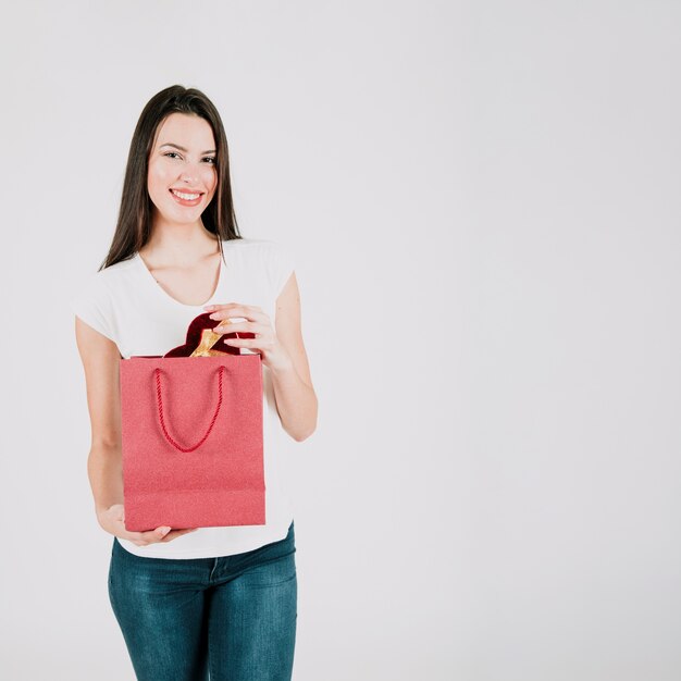 Femme souriante avec boîte de coeur dans un sac en papier