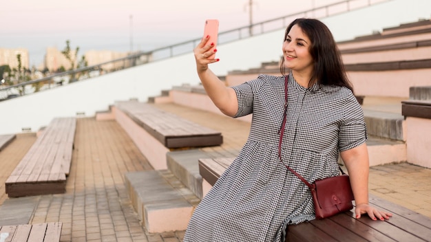 Femme souriante brune prenant un selfie