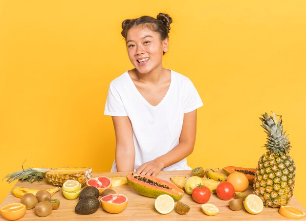 Femme souriante à la caméra derrière une table avec des fruits