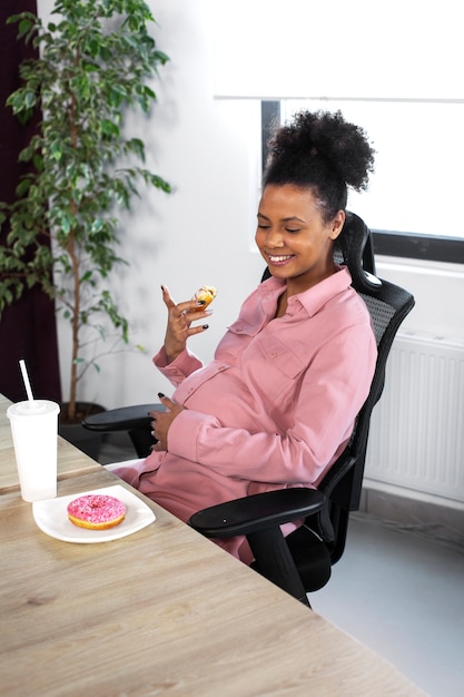 Photo gratuite femme souriante à coup moyen avec beignet