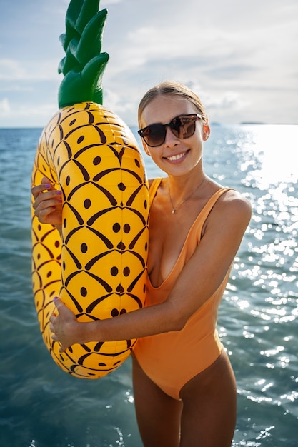 Photo gratuite femme souriante à coup moyen avec flotteur d'ananas