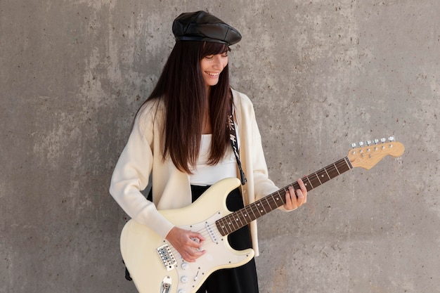 Photo gratuite femme souriante de coup moyen jouant de la guitare