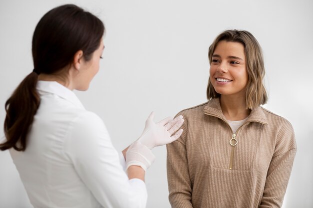 Femme souriante à coup moyen et médecin à la clinique