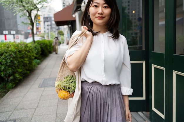 Femme souriante à coup moyen avec sac fourre-tout en ville