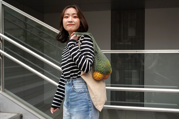 Femme souriante à coup moyen avec sac en tissu