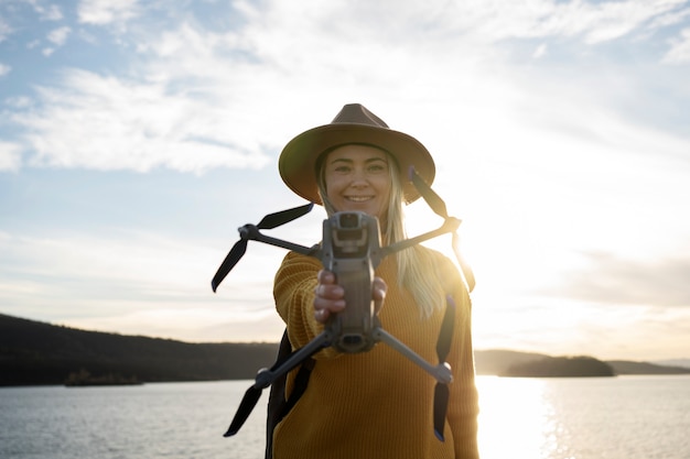 Photo gratuite femme souriante à coup moyen tenant un drone