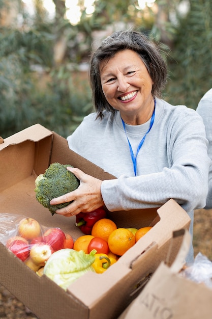 Femme souriante de coup moyen tenant un légume