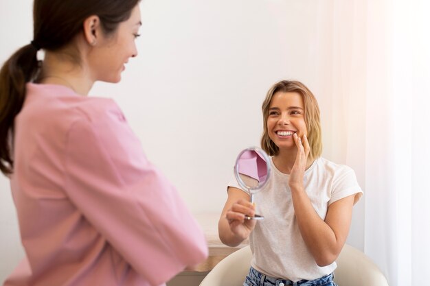 Femme souriante à coup moyen tenant un miroir